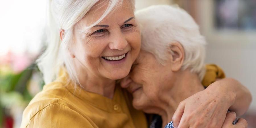 Vrouw houdt oudere vrouw in haar armen Vrouw houdt oudere vrouw in haar armen